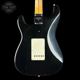 Black electric guitar with a visible brand logo on a black background