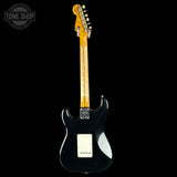 Black electric guitar with a visible brand logo on a black background