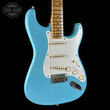 Blue electric guitar with a white pickguard on a black background, featuring the Tone Shop logo.