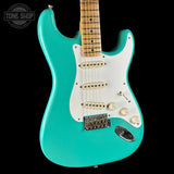 Turquoise electric guitar with a white pickguard on a black background, featuring the Tone Shop logo.