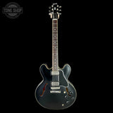 Black electric guitar on a black background with 'Tone Shop' logo.