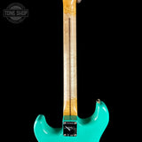 Turquoise electric guitar with a black background and 'Tone Shop' logo.