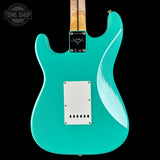 Turquoise electric guitar with a visible brand logo on a black background