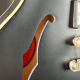Close-up of a guitar's soundhole and control knobs on a dark background
