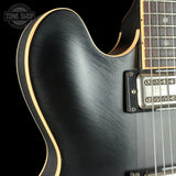 Close-up of a black electric guitar with a visible brand logo in the corner.