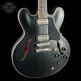 Black electric guitar with a visible brand logo on a black background