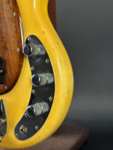 Close-up of a yellow guitar with metal hardware on a dark background