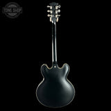 Black electric guitar on a black background with 'Tone Shop' logo.