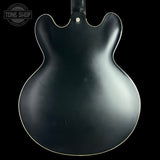 Black electric guitar body with 'Tone Shop' logo in the corner.