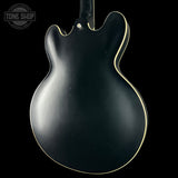 Black electric guitar body with a visible brand logo in the corner.