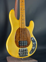 Yellow electric bass guitar with a wooden body on a dark background