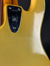 Close-up of a guitar's pickguard with a brand logo on a yellow background