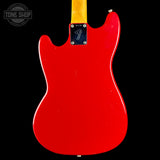 The back of a Fender electric guitar with a glossy red body and a natural maple neck, shown against a solid black background.