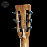 Close-up of a guitar headstock with tuning pegs on a black background, featuring the Tone Shop logo.