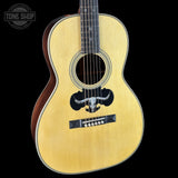 Acoustic guitar with bull logo on a black background, featuring the Tone Shop logo.