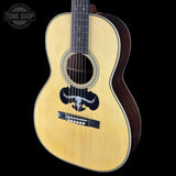 Acoustic guitar with a bull logo on a black background, featuring the Tone Shop logo.