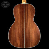 Back view of a wooden acoustic guitar with 'Tone Shop' logo.
