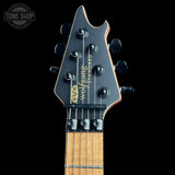 Close-up of the headstock of a Wolfang Standard E/V/H electric guitar against a black background, showing the black headstock with gold lettering and six tuning pegs.