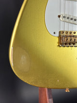 Close-up of a gold electric guitar with a dark background