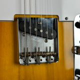 Close-up of a Fender electric guitar body showing the bridge, pickup coil, and part of the sunburst finish.
