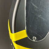 Close-up of a black motorcycle helmet with a bright yellow accent stripe and a visible screw fastener near the lower edge.