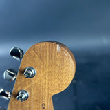 Close-up of a guitar headstock with tuning pegs against a blurred blue background