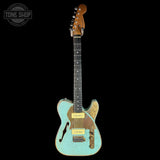 Vintage turquoise electric guitar with a worn finish on a black background, featuring the Tone Shop logo.
