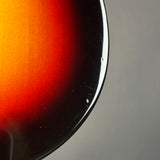 Close-up of a glossy sunburst guitar body edge showing a red, orange, and black gradient against a neutral gray background.