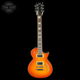 An electric guitar with a sunburst orange body, black headstock, and gold hardware, shown against a solid black background with a Tone Shop watermark in the top-left corner.