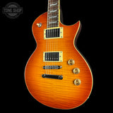 A Gibson Les Paul Custom electric guitar with a vibrant orange-to-brown flame finish, featuring gold hardware and a dark fretboard, shown against a solid black background.