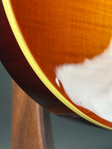 Close-up detail of an acoustic guitar body showing the glossy sunburst finish, cream edge rosette, and dark wood neck joint.