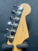 Guitar headstock with tuning pegs on a dark background