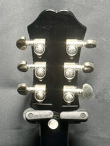 Guitar headstock with tuning pegs on a gray background