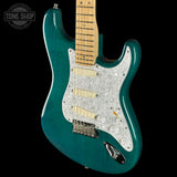 Teal electric guitar with a pearlized pickguard on a black background, featuring 'Tone Shop' branding.
