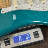 Teal electric guitar on a digital scale displaying weight