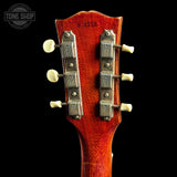 Close-up of a guitar headstock with tuning pegs on a black background, featuring the Tone Shop logo.
