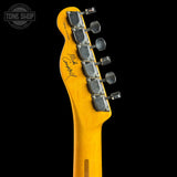 Close-up of the headstock of a yellow-finish electric guitar on a black background, showing six chrome tuning pegs and a visible 'Tone Shop' watermark in the top left corner.