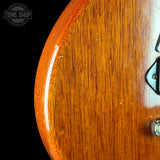 Close-up of a guitar's wooden finish with 'Tone Shop' logo.