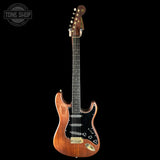 Electric guitar with a wooden finish on a black background, featuring the Tone Shop logo.
