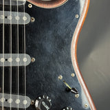 Close-up of a black electric guitar with wood finish on a gray background