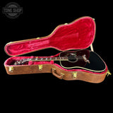 Guitar in a brown case with red interior on a black background, featuring 'Tone Shop' logo.