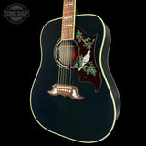 Black acoustic guitar with decorative inlay on a black background, featuring the Tone Shop logo.