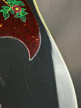 Close-up of a guitar's tortoiseshell pickguard with floral design.
