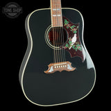 Black acoustic guitar with decorative inlay on a black background