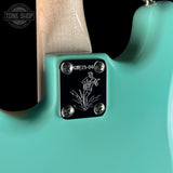 Close-up of a turquoise electric guitar with a brand logo in the corner.