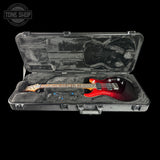 Red electric guitar in a hard-shell case with 'Tone Shop' logo.