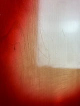 A close-up of a glossy red surface with a vertical gradient blending into a warm beige/tan area, showing faint scratches and a light reflection.
