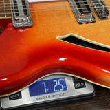 Close-up of a sunburst electric guitar body resting on a digital scale displaying 7.25 oz.