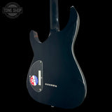 The rear view of a glossy black electric guitar body, featuring a clear pickguard, silver control knobs, and a red and blue circular sticker on the lower left, set against a solid black background.