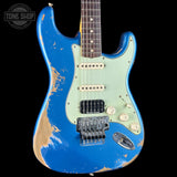 A Stratocaster-style electric guitar with a distressed blue finish and a pale mint green pickguard, shown against a black background. The guitar has visible wear and tear on the body, and a Tone Shop watermark is in the top-left corner.